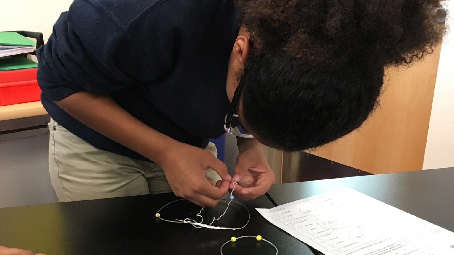 Photo of a student working on a wire atom model